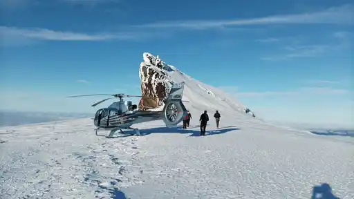 Helicopter Landing On Glacier Capped Mountain